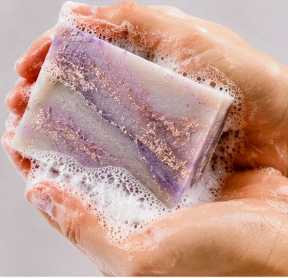 Plum soap lathering in hands - purple and gold swirl